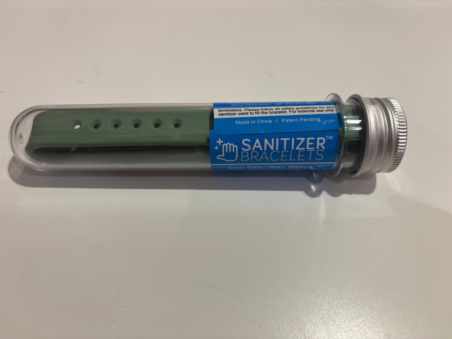 Green wristband in a clear plastic case with 'Sanitizer Bracelets' label on a white background